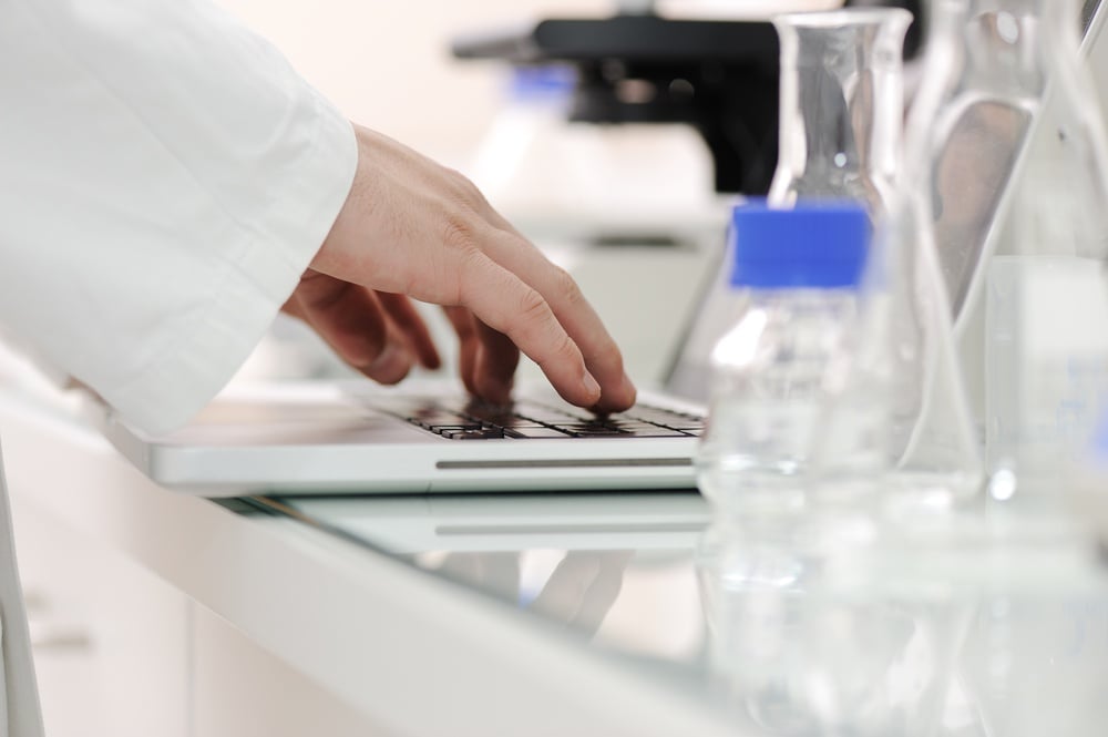 Scientist working at lab with laptop, microscope and tubes